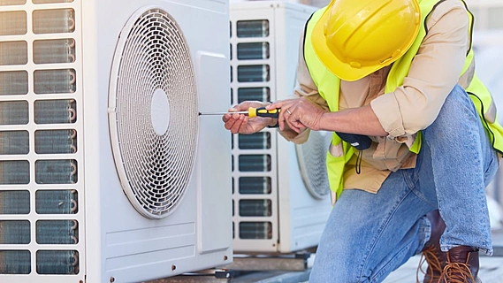 Technician servicing air conditioning equipment for a commercial property