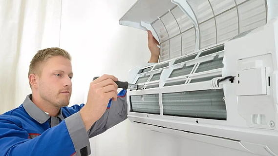 HVAC technician using a gauge to check the refrigerant pressure on an air conditioning unit