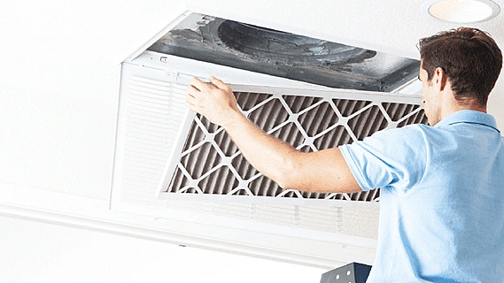 Rows of outdoor air conditioning condenser units on a building exterior under strong sunlight