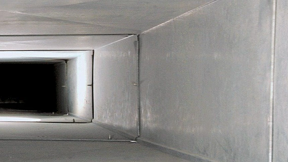 Clean white air conditioning vent and tidy room after professional duct cleaning
