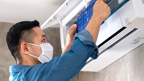 Technician inspecting a ceiling air conditioning vent inside a Dubai apartment